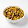 A white ceramic bowl filled with a rich, yellow-orange stewed meat and vegetable dish, set against a clean white background.