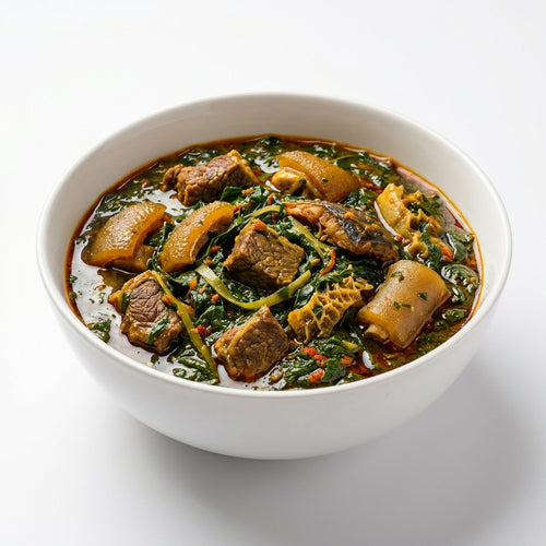 A white ceramic bowl filled with a rich, dark stew containing chunks of meat, yellowish-brown roots, and abundant green leafy vegetables, set against a clean white background.