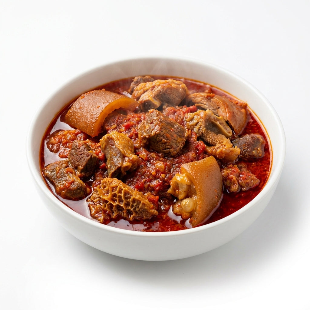 A white ceramic bowl filled with a rich, reddish-brown stew containing beef chunks, nettle, and a large piece of trotter, set against a clean white background.