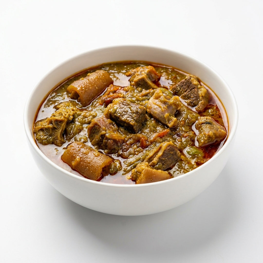 A white ceramic bowl filled with a rich, chunky stew containing green vegetables, brown root vegetables, and meat in a reddish-brown broth, set against a clean white background.