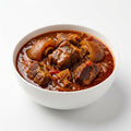 A white ceramic bowl filled with a rich, reddish-brown beef stew or curry, photographed from a top-down angle on a clean white background.
