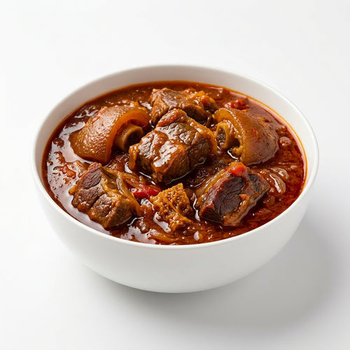 A white ceramic bowl filled with a rich, reddish-brown beef stew or curry, photographed from a top-down angle on a clean white background.
