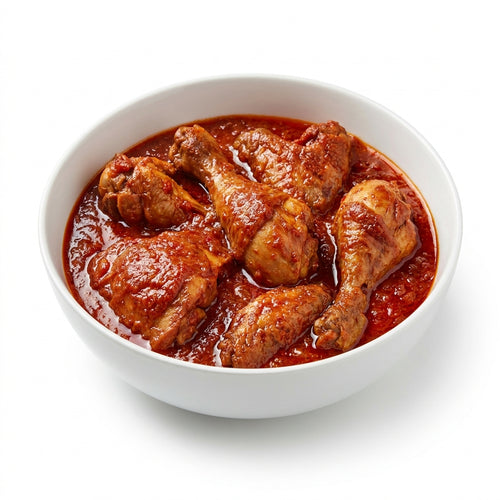 A white ceramic bowl filled with cooked chicken drumsticks and thighs in a rich, glossy red tomato-based sauce, set against a clean white background.